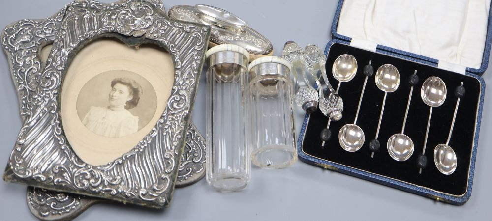 Two early 20th century silver photo frames, a cased set of 6 silver coffee spoons, a silver mounted buffer, knife rests and two ivory t